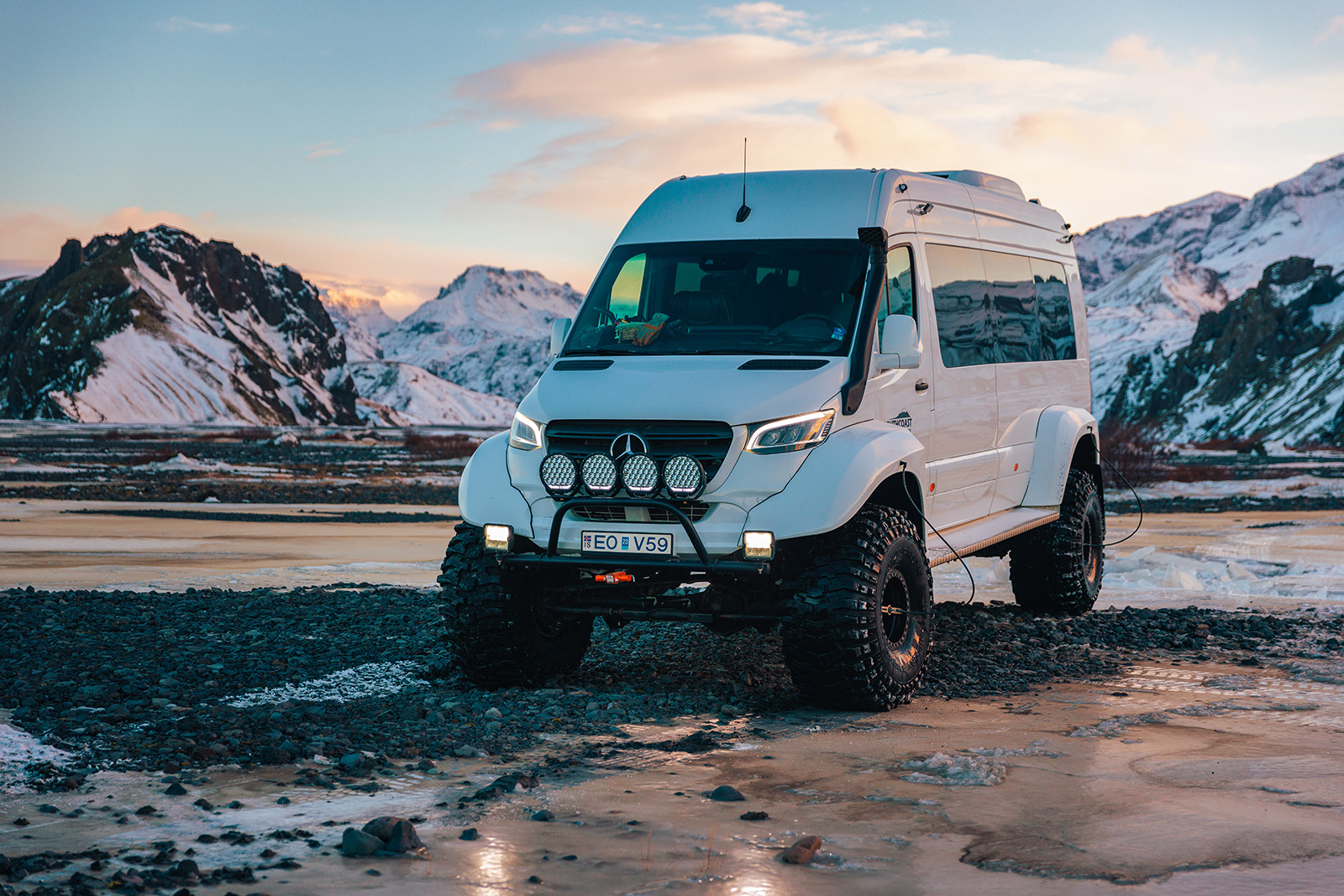 Modified white van with big wheels on a wet road