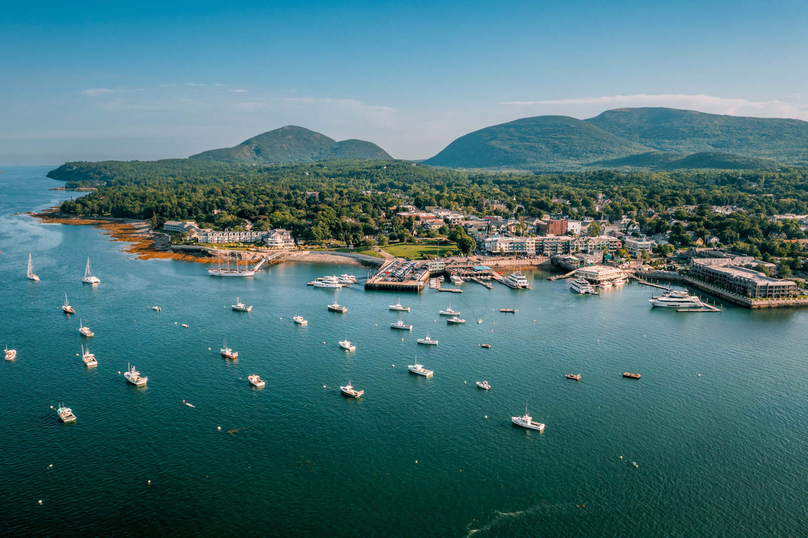 Boats scattered throughout the ocean next to a seaside town