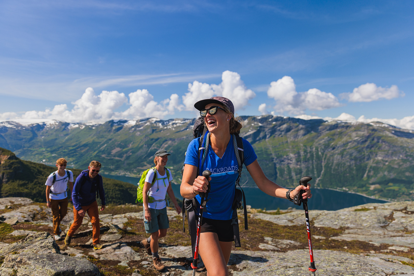 Woman with walking sticks smiling at another group of hikers