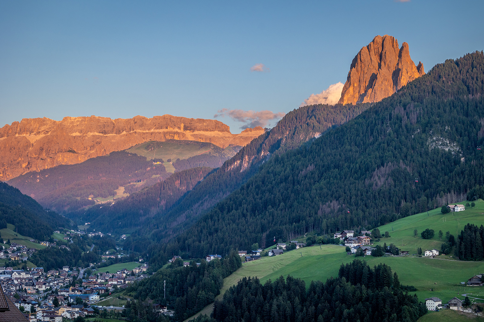 View of large hills covered in trees, with tall mountains in the distance