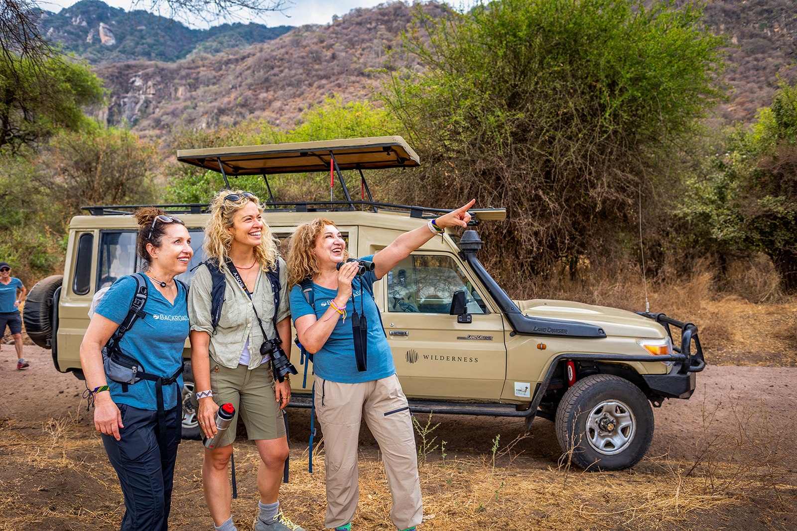Three women in front of a truck pointing