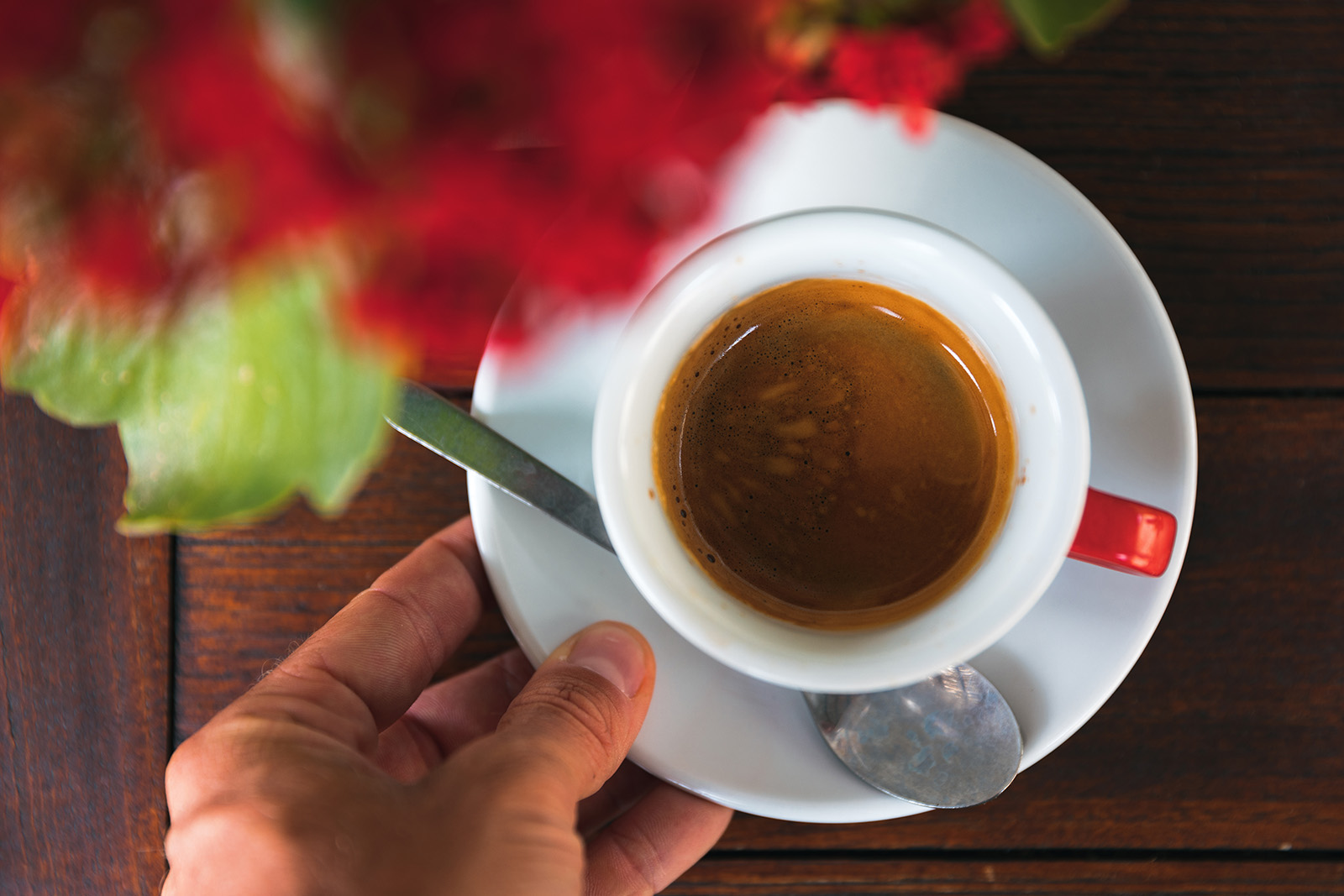 Hand holding a cup of coffee on a plate