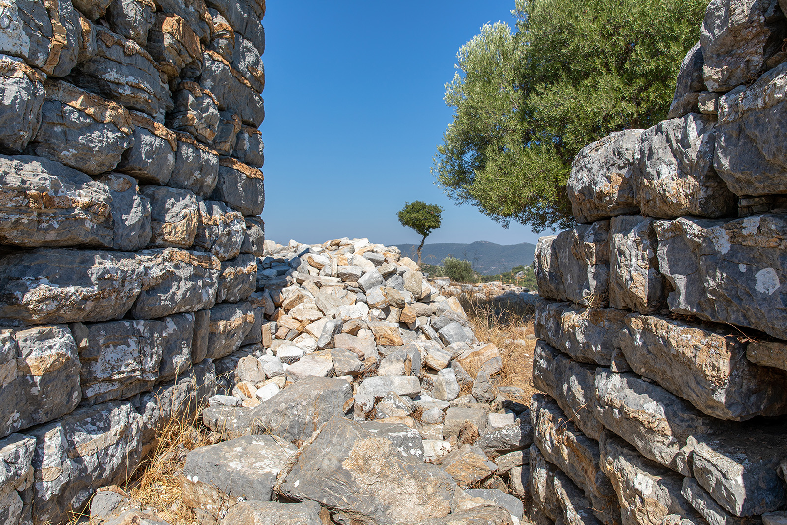 Stone ruins with piles of stone in between two buildings