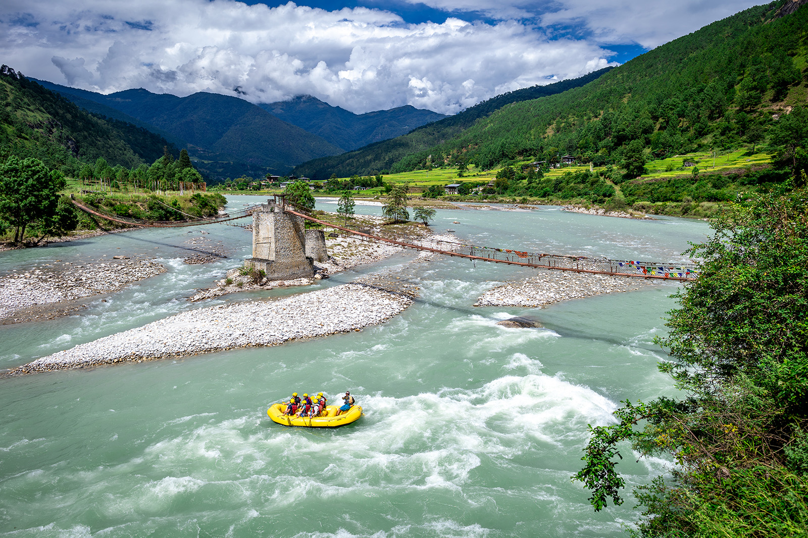 Group of people rafting in a river on a yellow boat