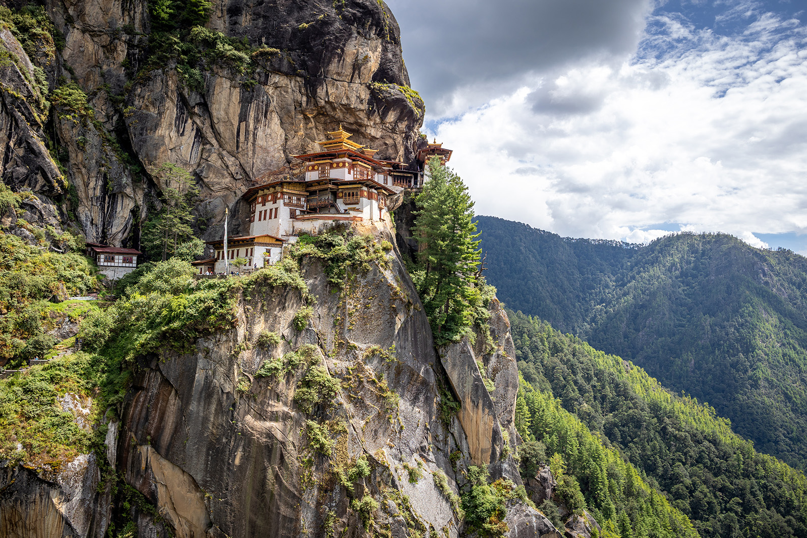 Large white temple on top of a cliff, with a valley in the distance