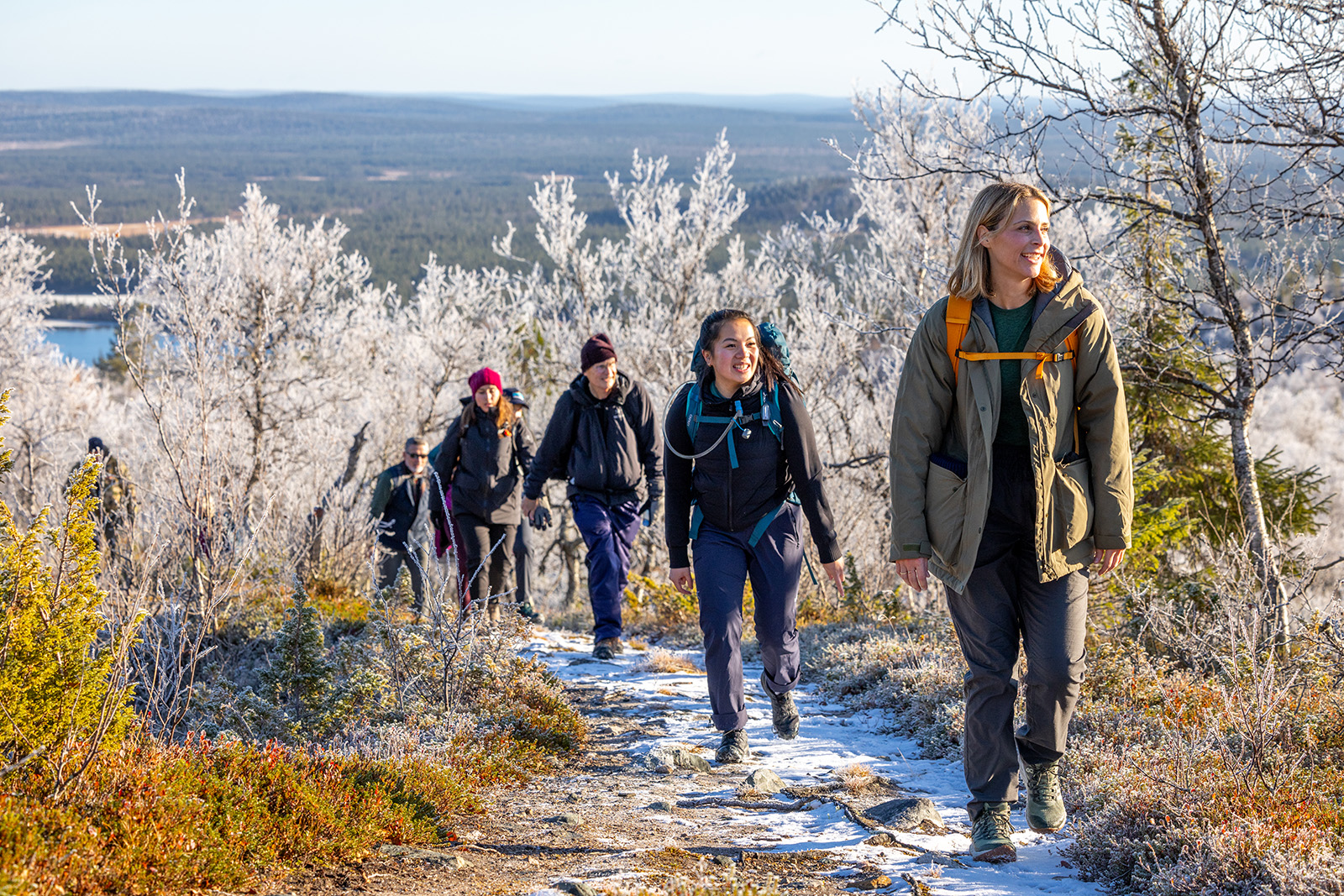 Group of hikers wearing backpacks, ascending a snowy trail