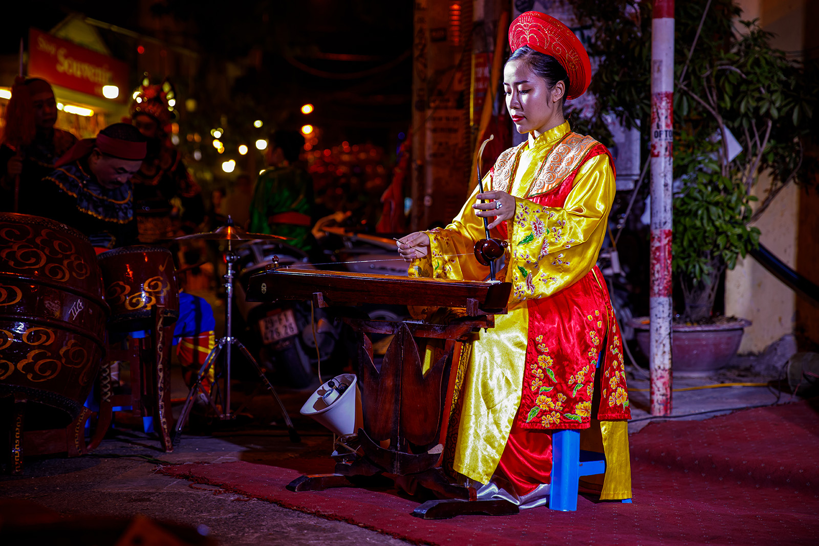Woman playing a traditional instrument while wearing a traditional outfit