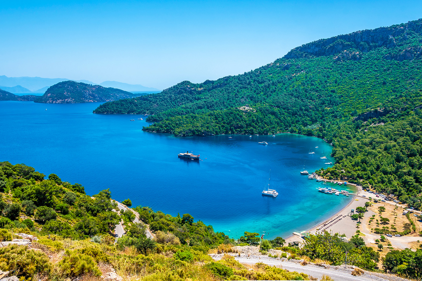 Coastal beach with tall, tree-covered mountains on the right