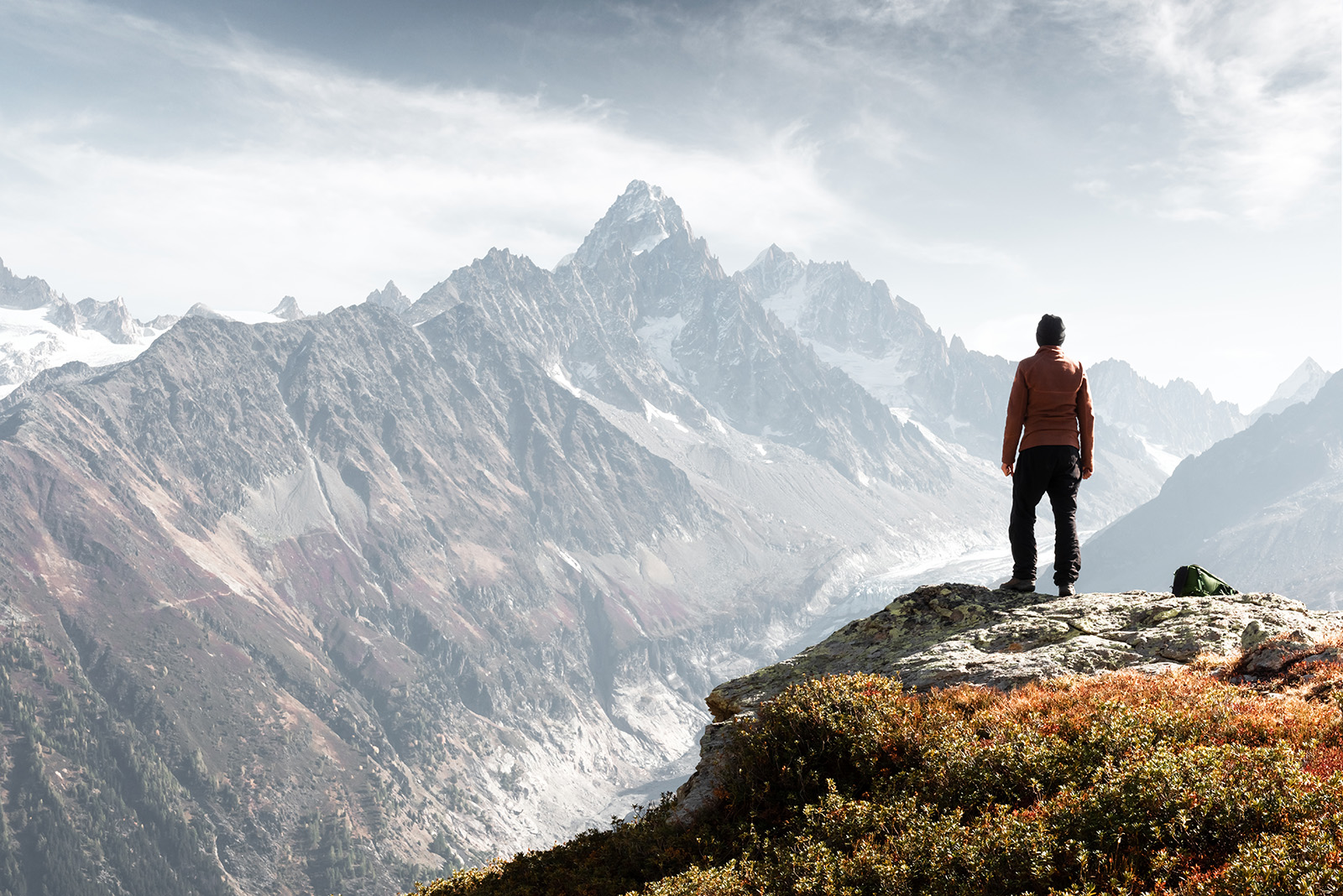 Man standing on a cliff, looking out to foggy mountains