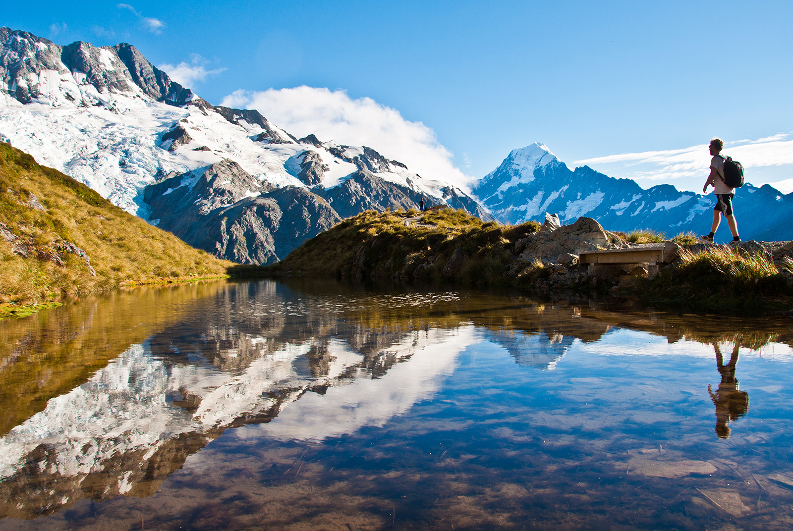Man walking on a rocky path with snowy mountains in the distance