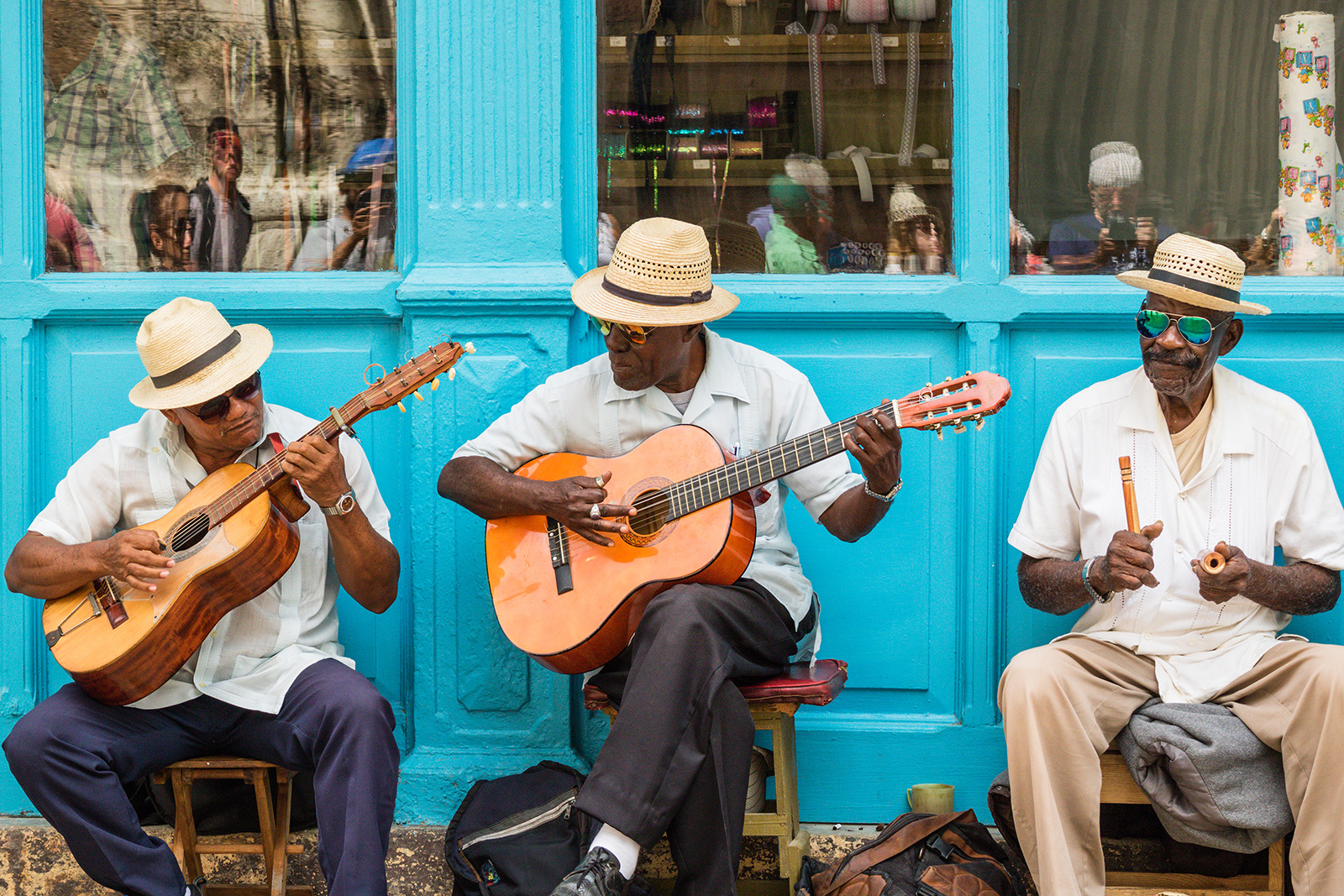 Three men playing the guitar while sitting down