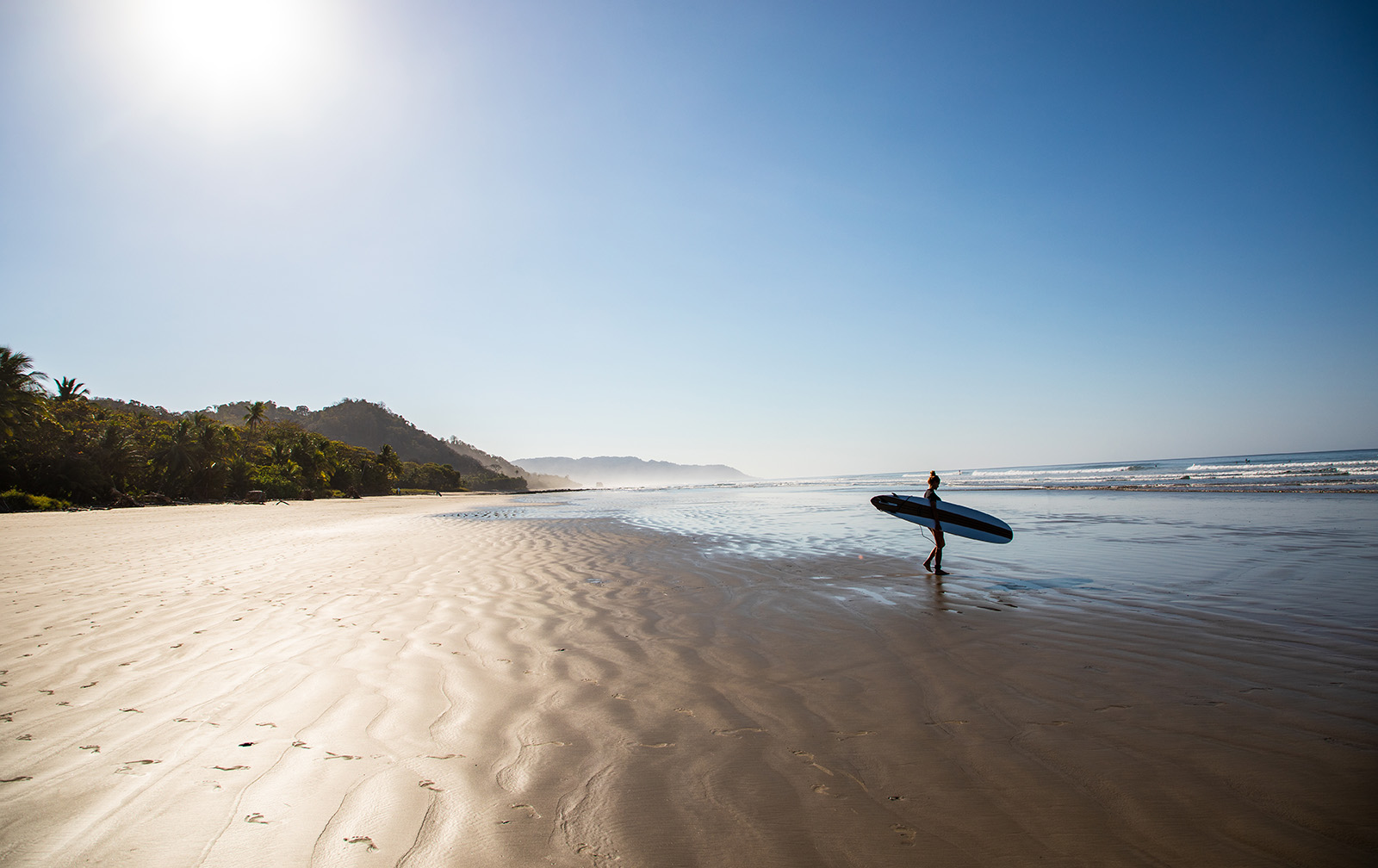 Woman holding a surfboard while standing on the beach