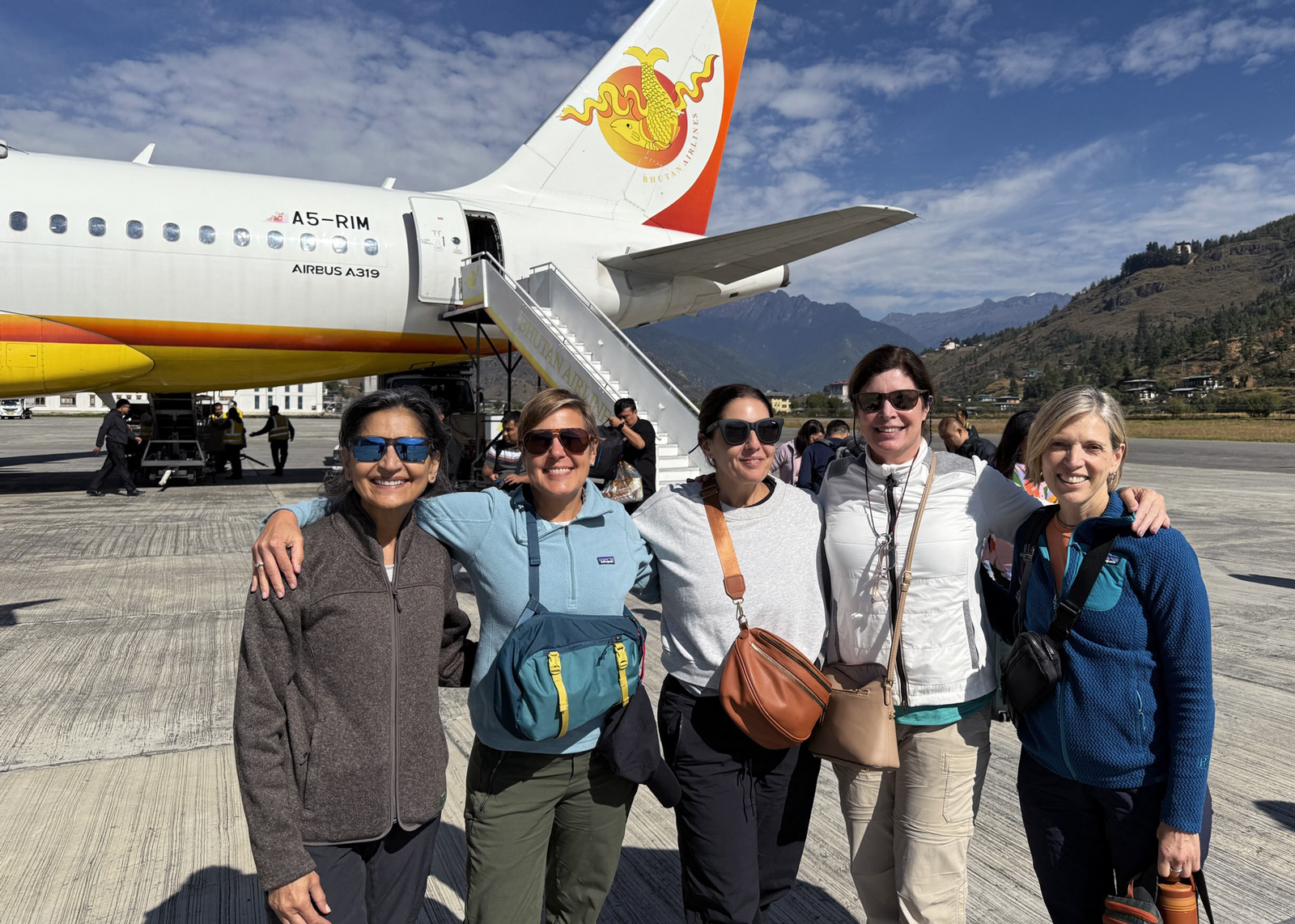Group of women smiling and standing in front of a plane