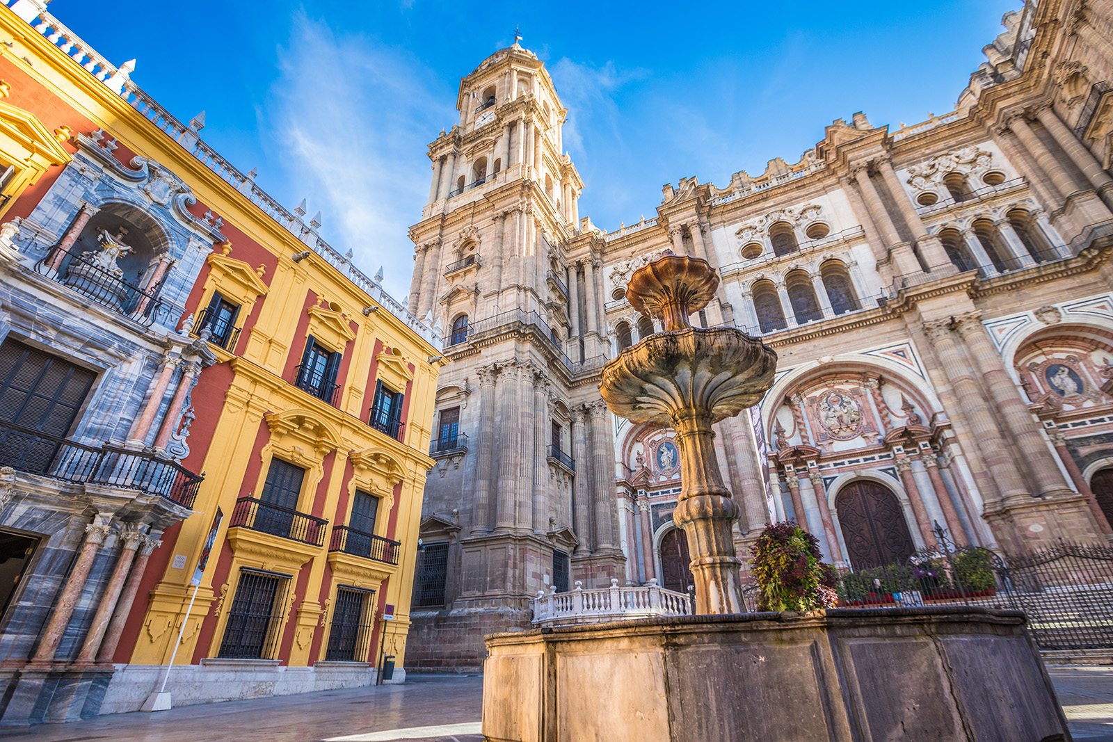 Castle-like cathedral in a town center with a fountain in front