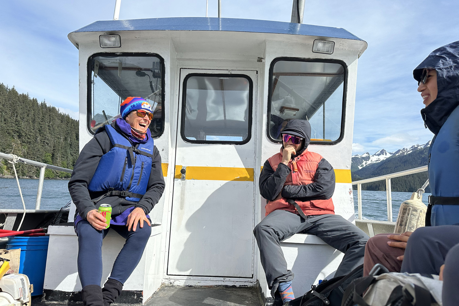Three men smiling while sitting on a boat