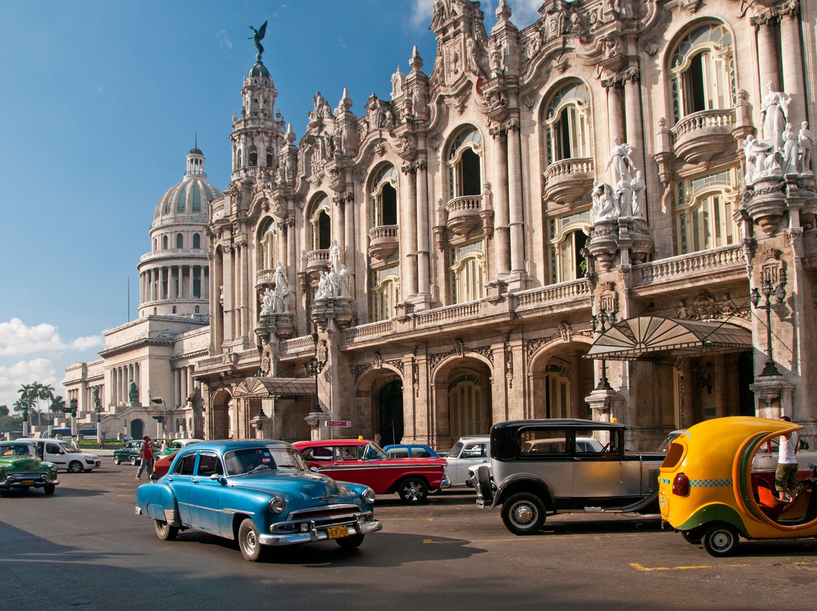 Exterior view of large palace building with old school cars in front