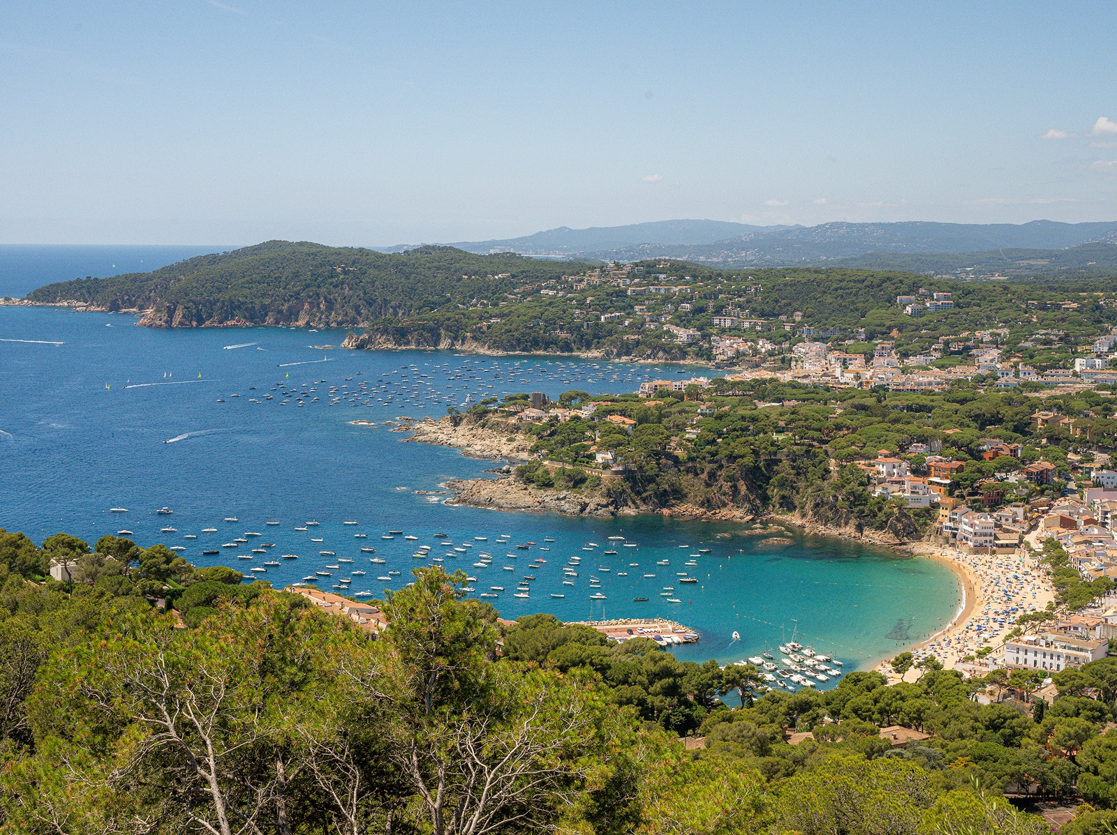 Sky view of a town and a beach with boats floating in the water