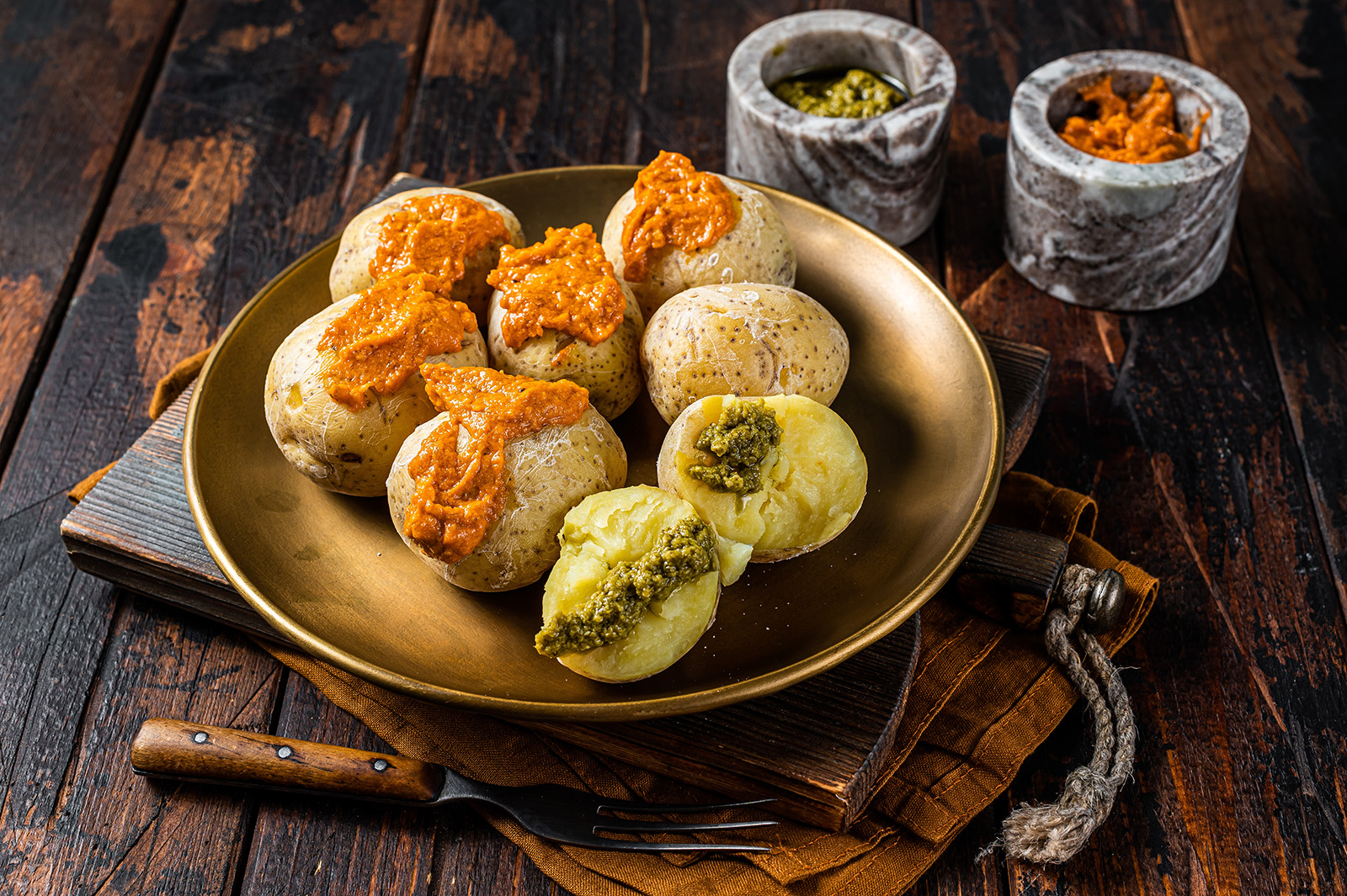 Plate of cooked potatoes with two small dishes of sauce on the side