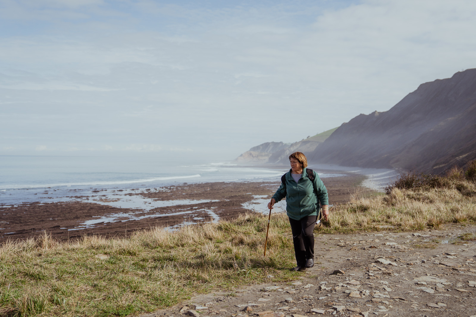 Woman walking through a dirt trail by the ocean