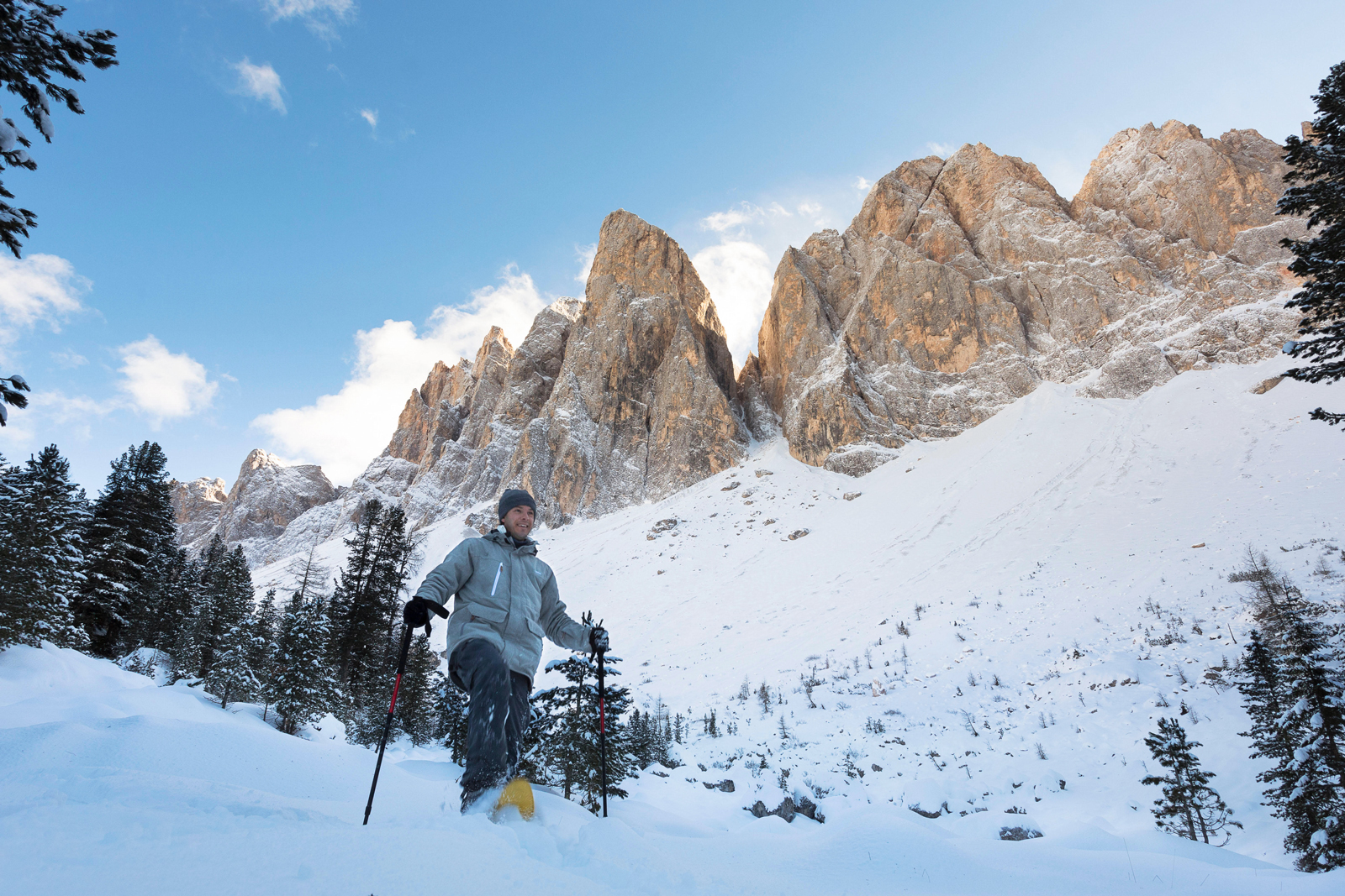Man with hiking poles, walking through a valley covered in thick snow