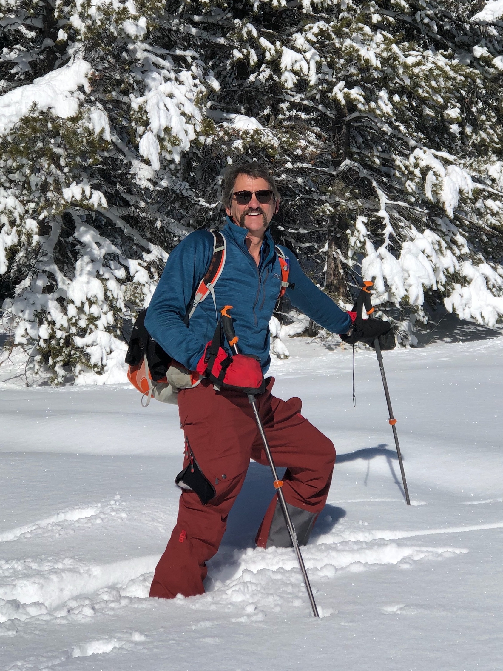 Man with hiking poles, walking through thick snow