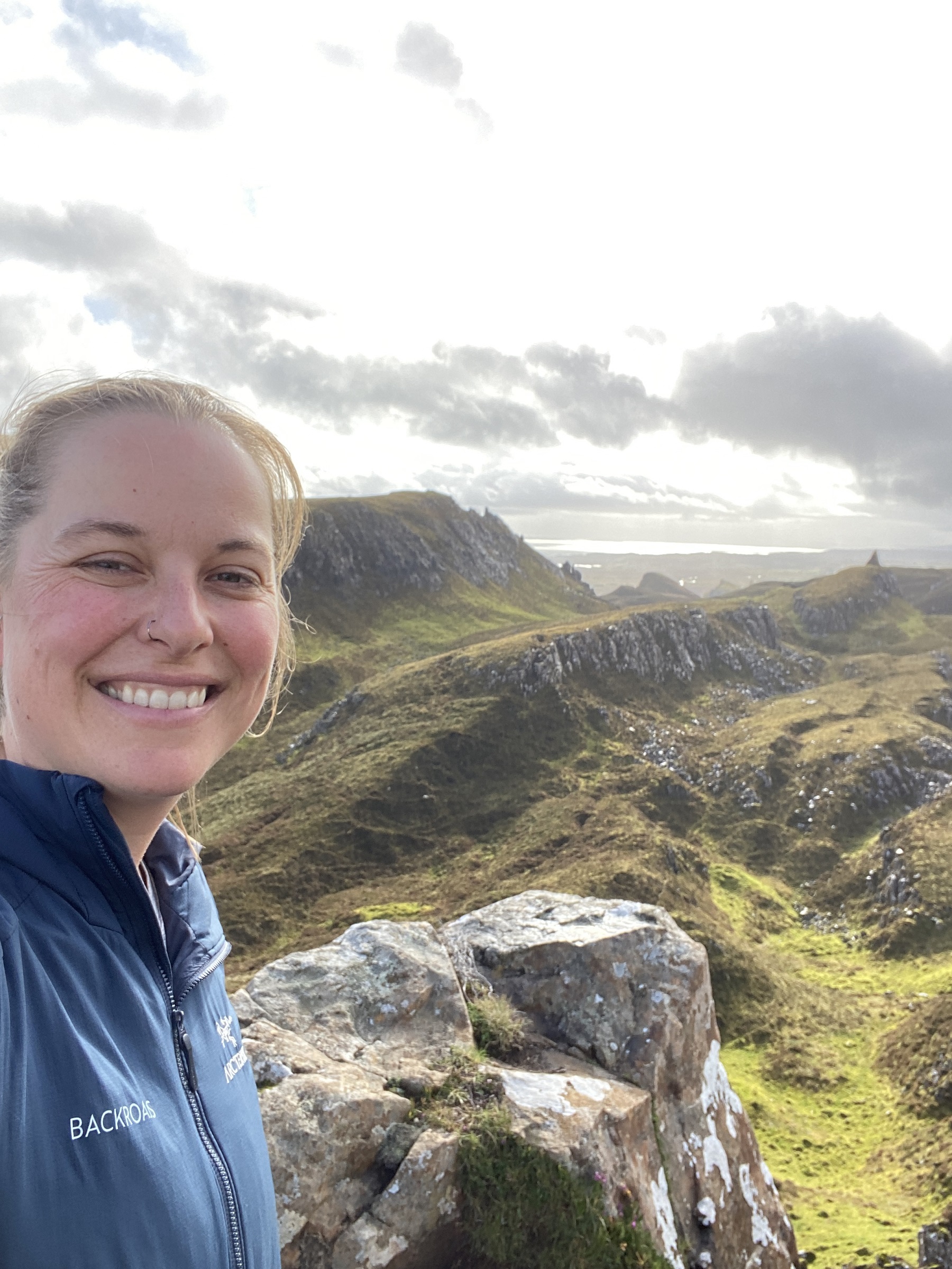 Woman smiling with a large valley of mountains in the background
