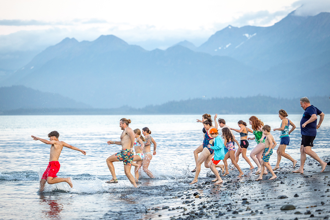 Group of families running into the ocean at the beach