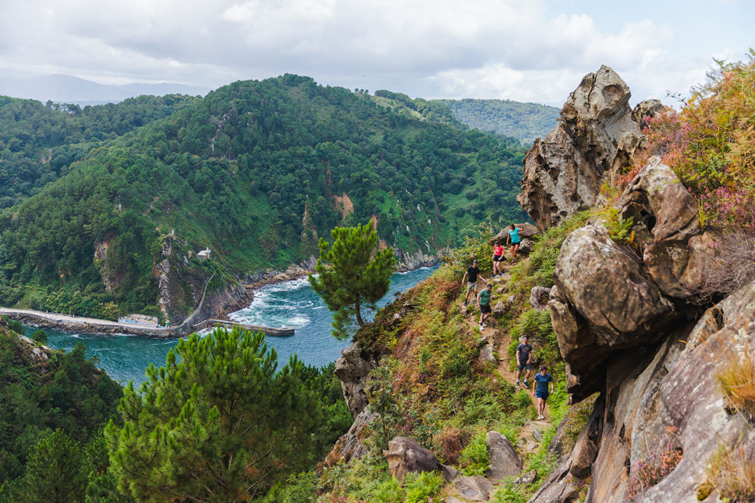 Group of hikers descending a large mountain with a river and hills in the distance