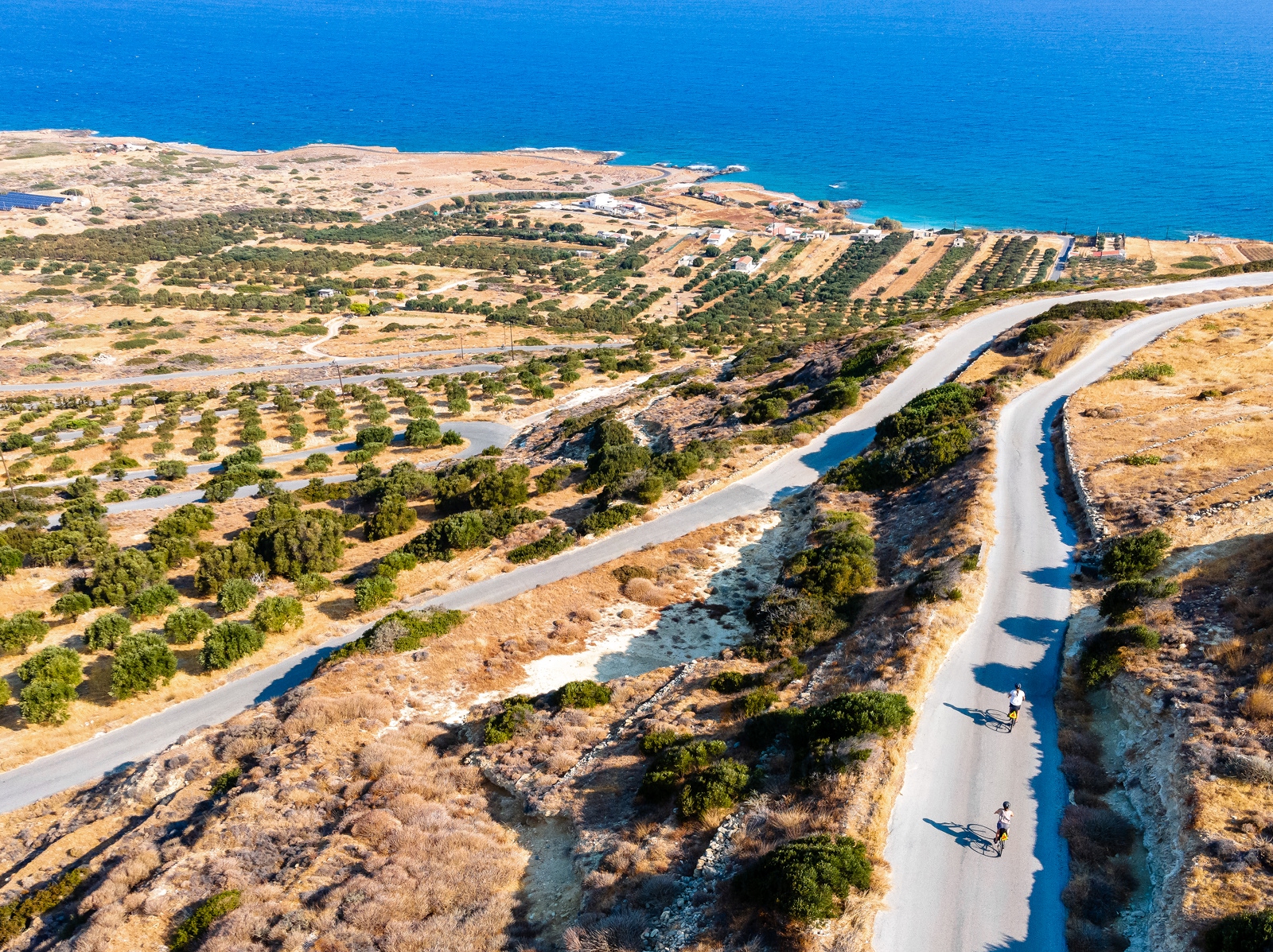 Long, empty roads with people biking, with the ocean in the distance