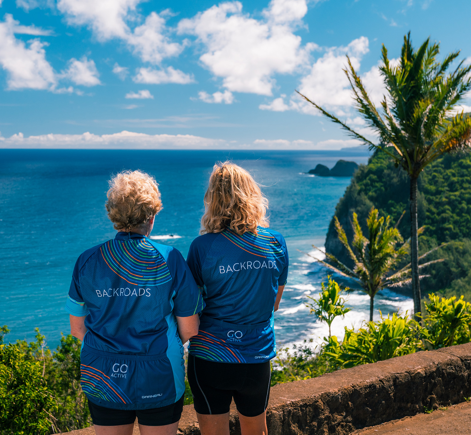 Two women wearing Backroads jerseys, looking out to the ocean