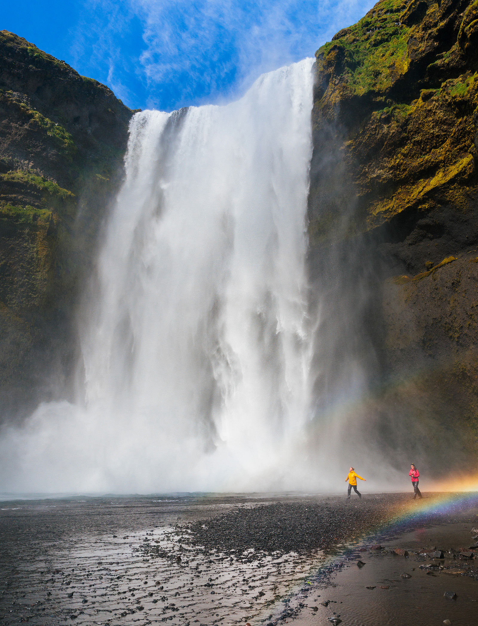 Large waterfall with two people walking on the ground level