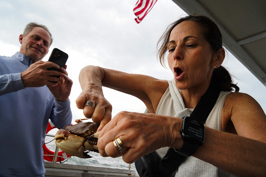 Woman holding a lobster while a man takes a photo