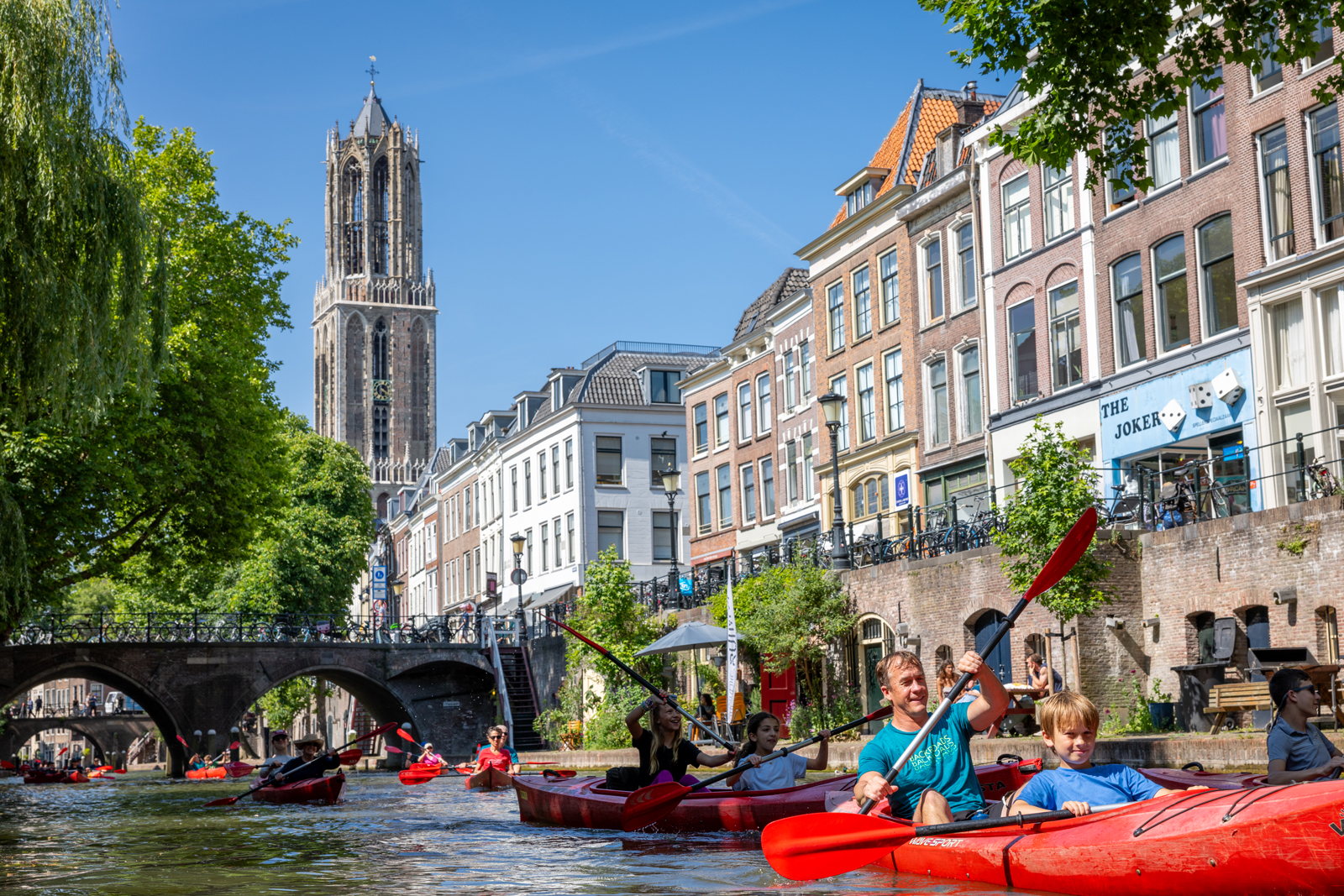 People paddling in red kayaks in a town river