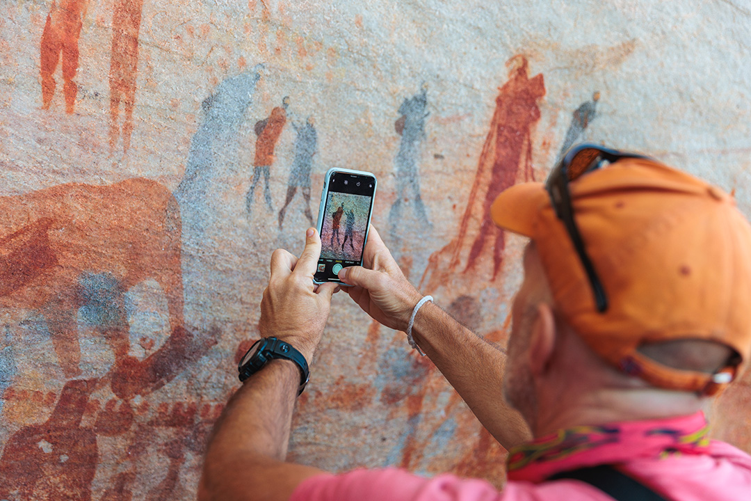 Person taking a photo on their phone of paintings on the walls