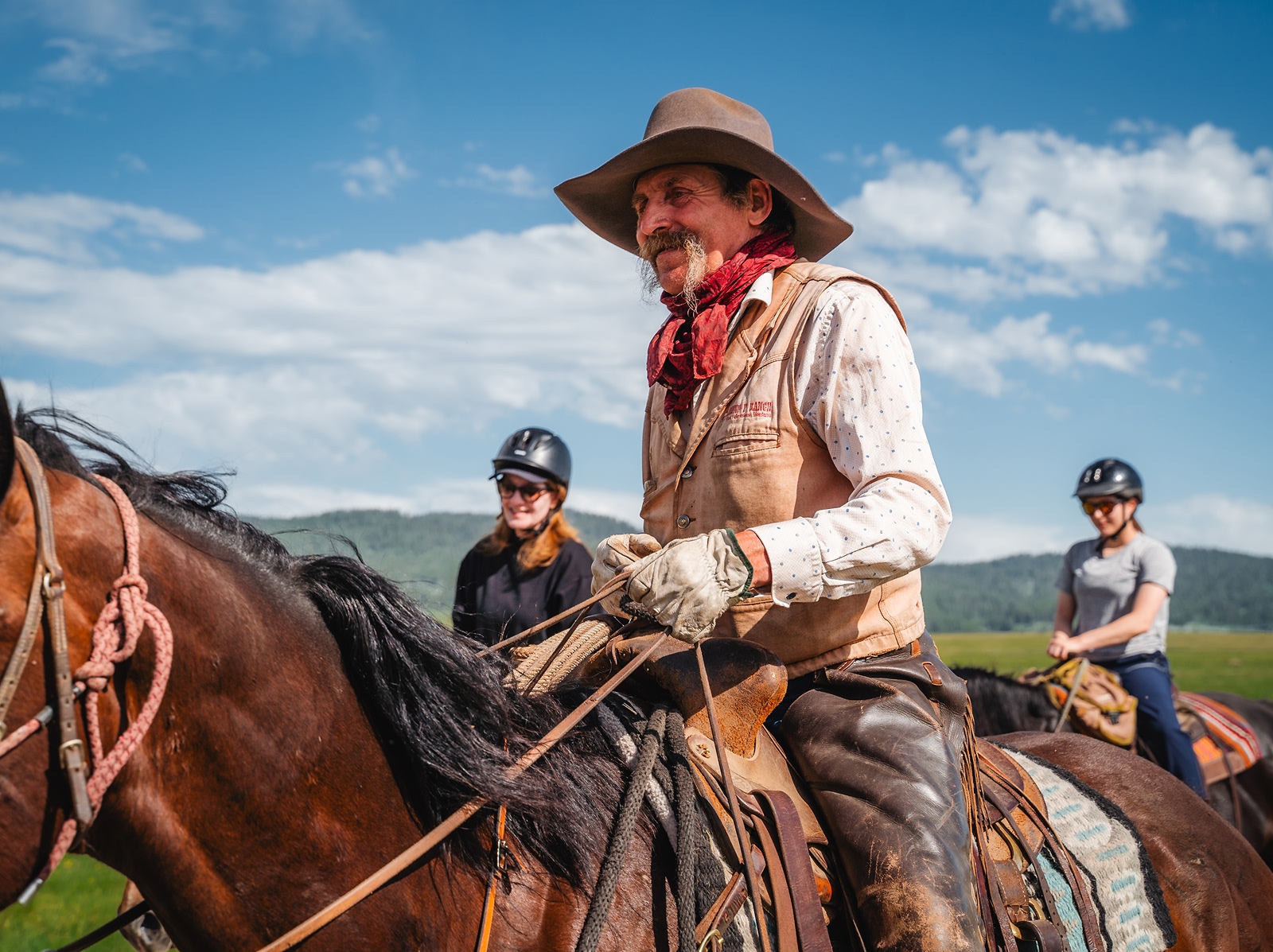 Man with cowboy gear and a long beard horseback riding