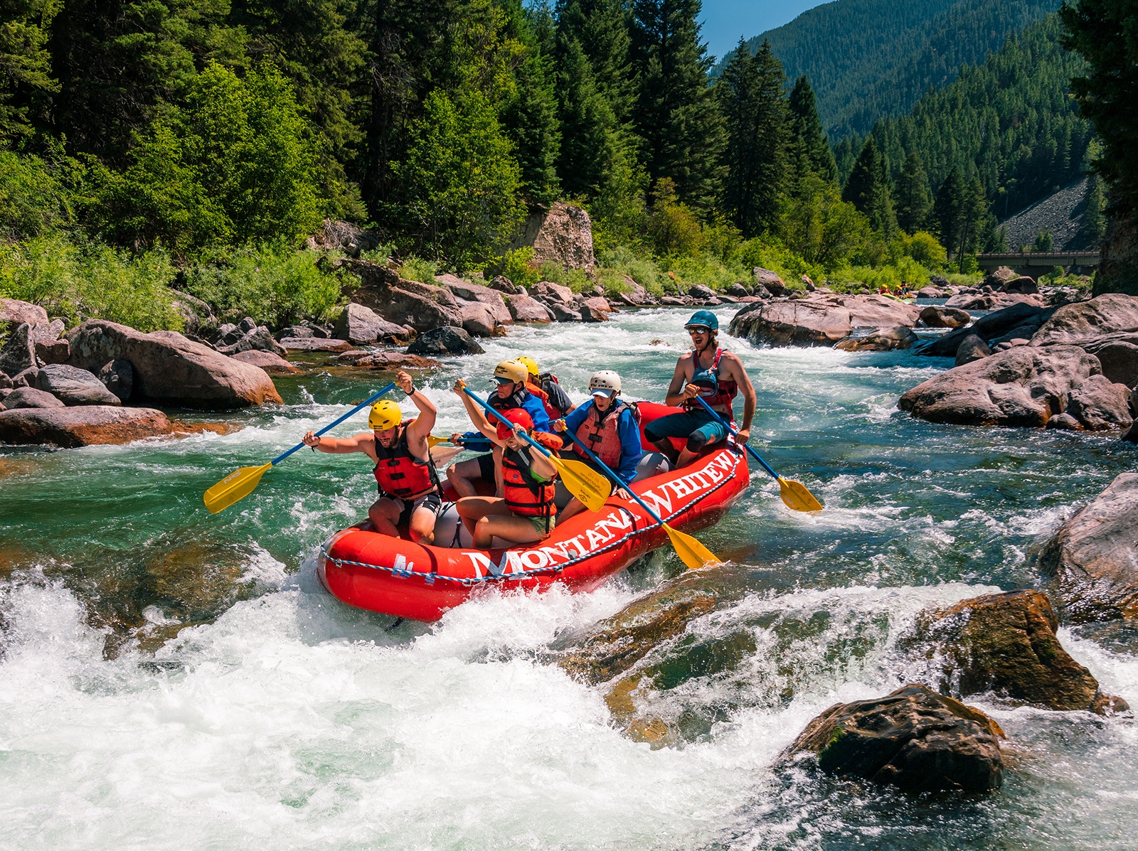 Group of people on a red raft, paddling