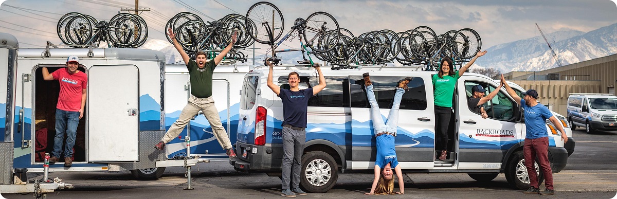 Group of people in front of vans with bikes on top