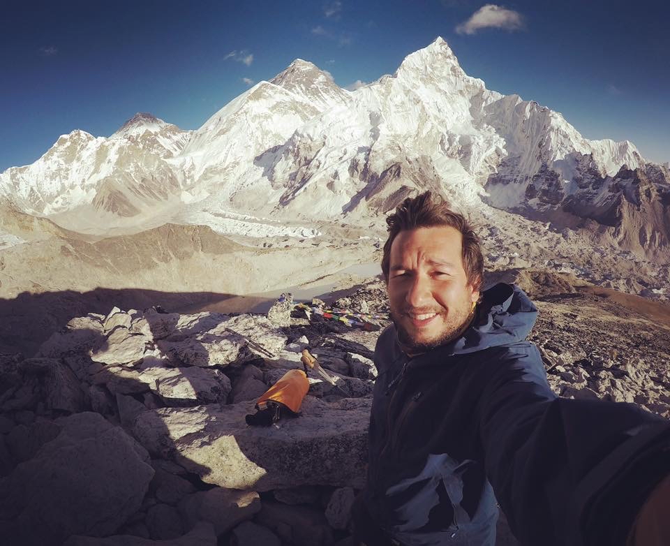 Man taking a selfie with snow mountains in the background