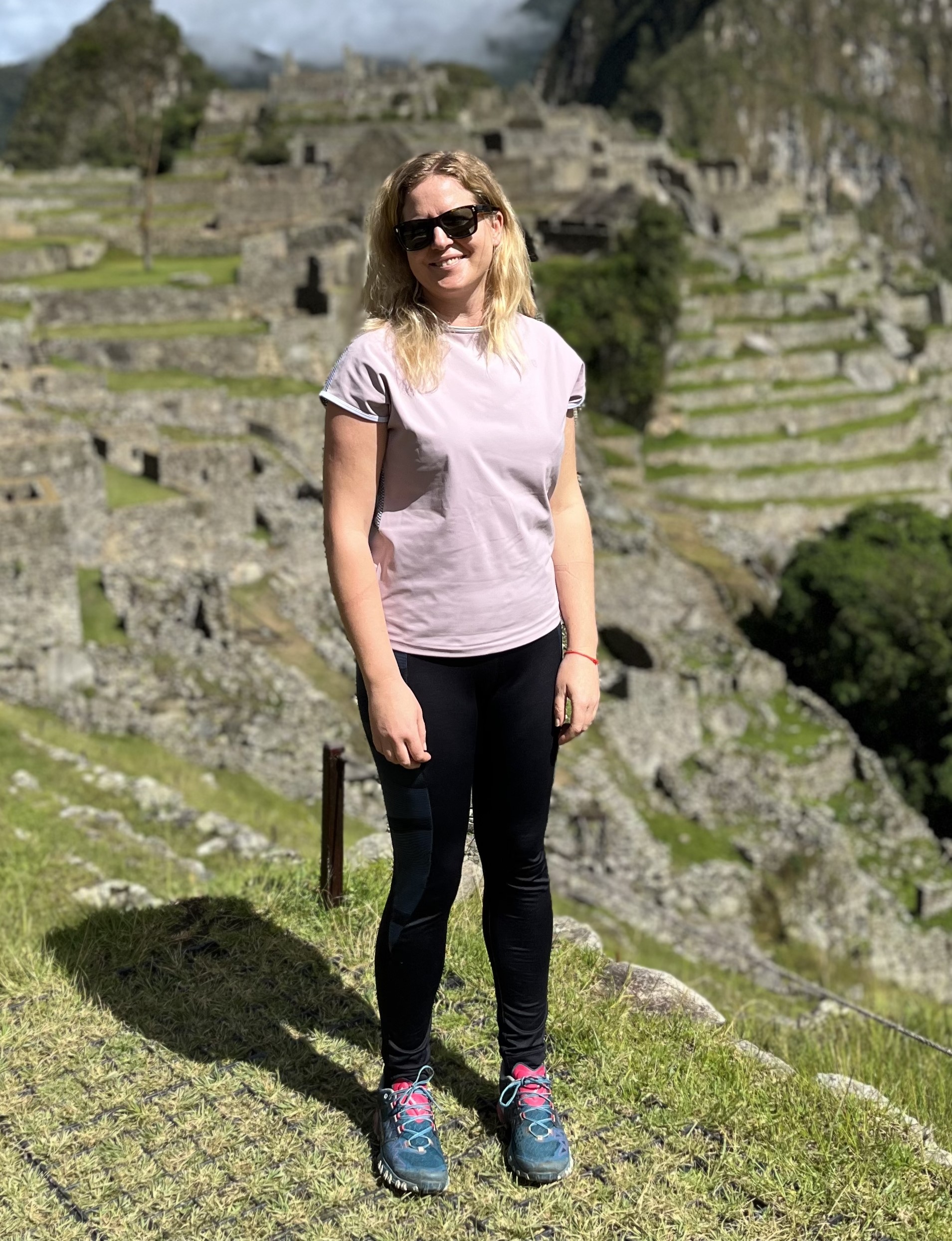 Woman in a pink shirt, smiling with valleys in the background