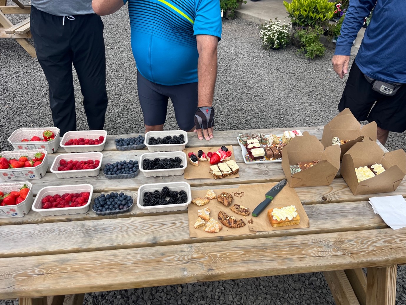 Table with small trays full of mixed berries, with a group of people in front