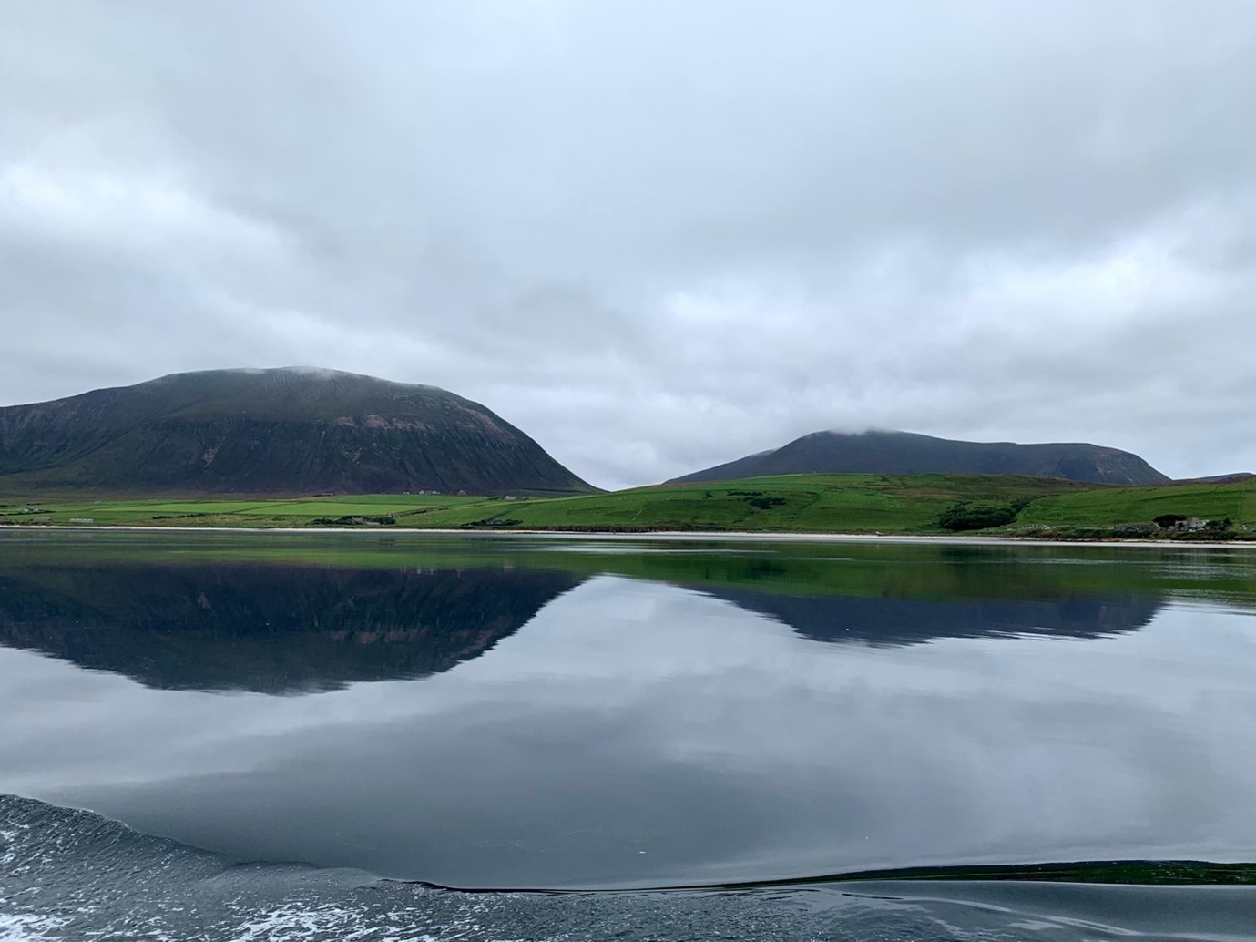 Large lake with tall hills covered in fog in the background