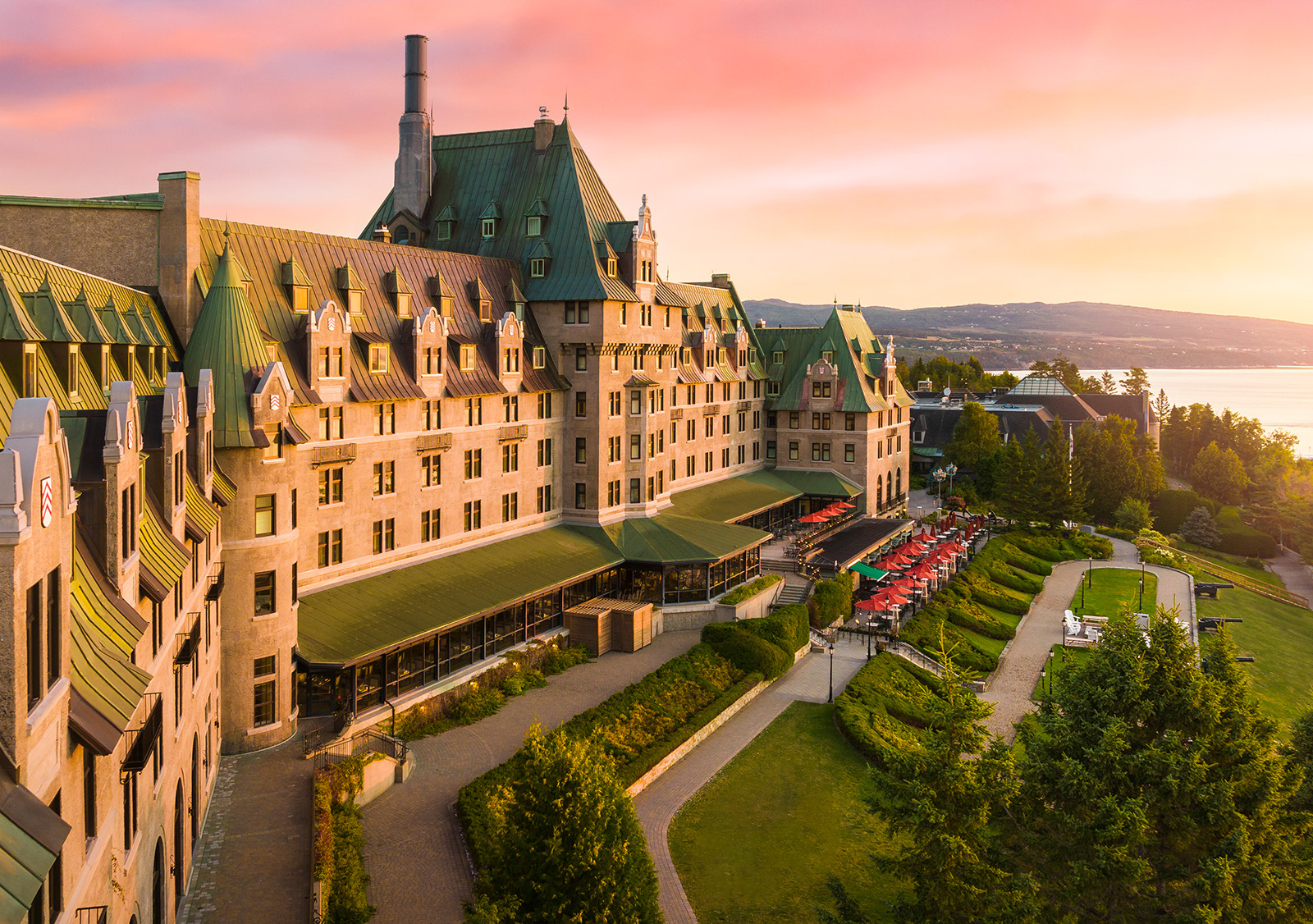 Exterior view of multi-story hotel building with green roofing, and large grass fields in front