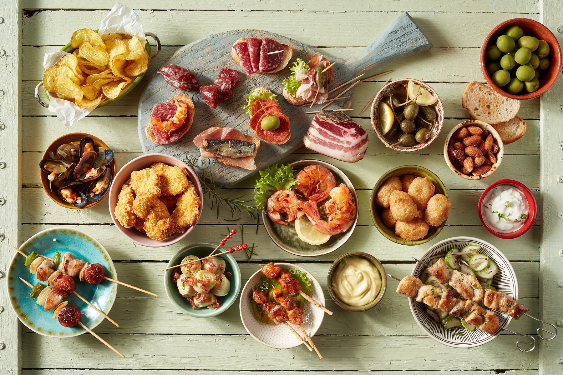 Table with a spread of multiple bowls and plates of grilled meats and vegetables