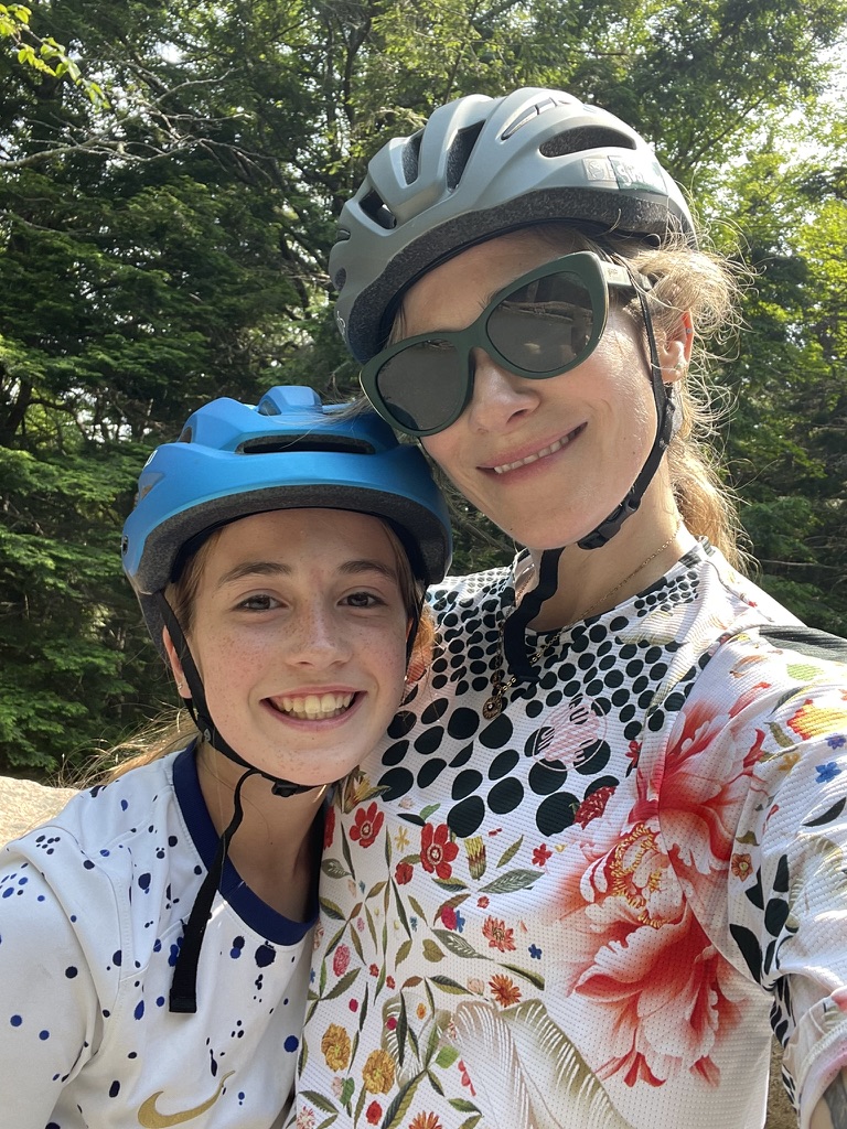 Mother and daughter wearing biking gear, smiling while hugging