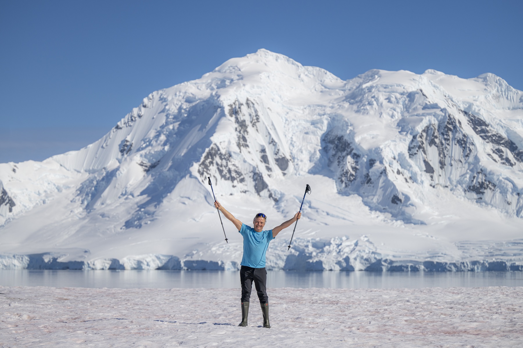 Man standing with arms open in the middle of a valley full of snow