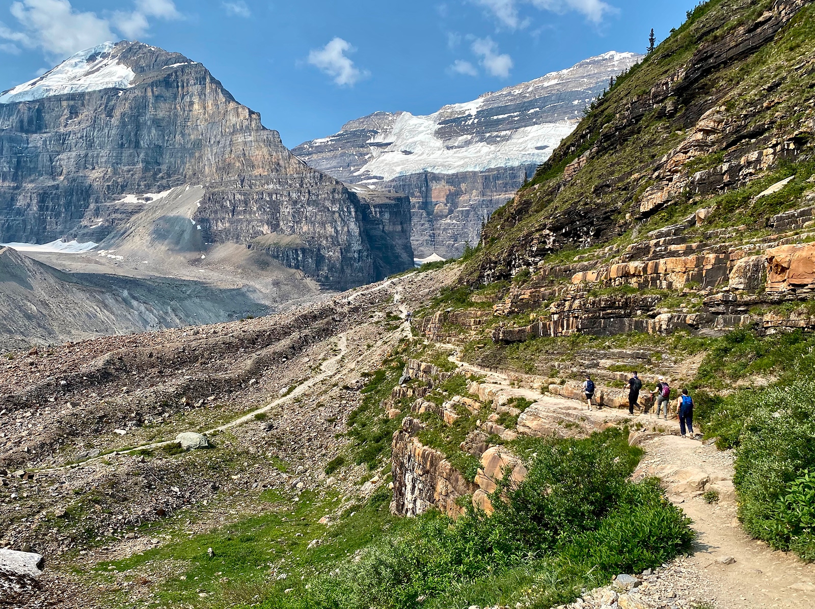 Group of people hiking along a dirt trail with large mountains in the distance