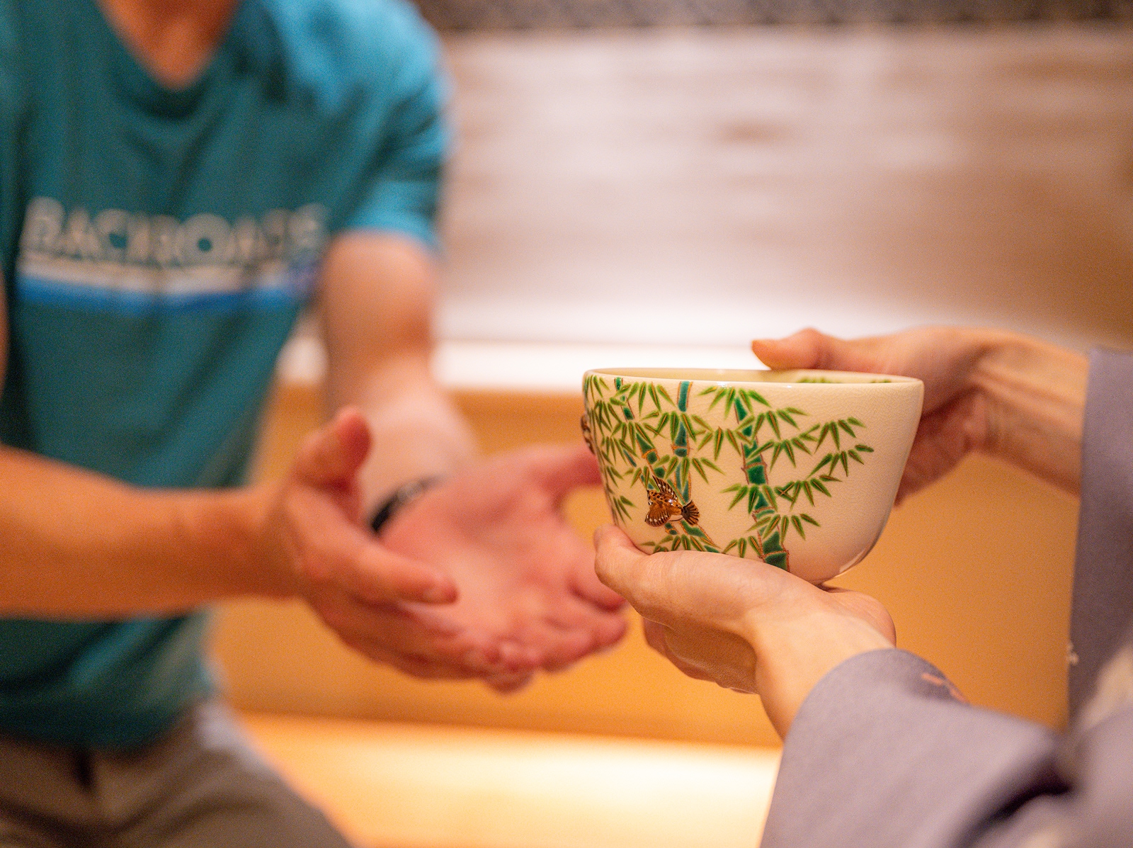 Person passing a large cup to a person with their arms out