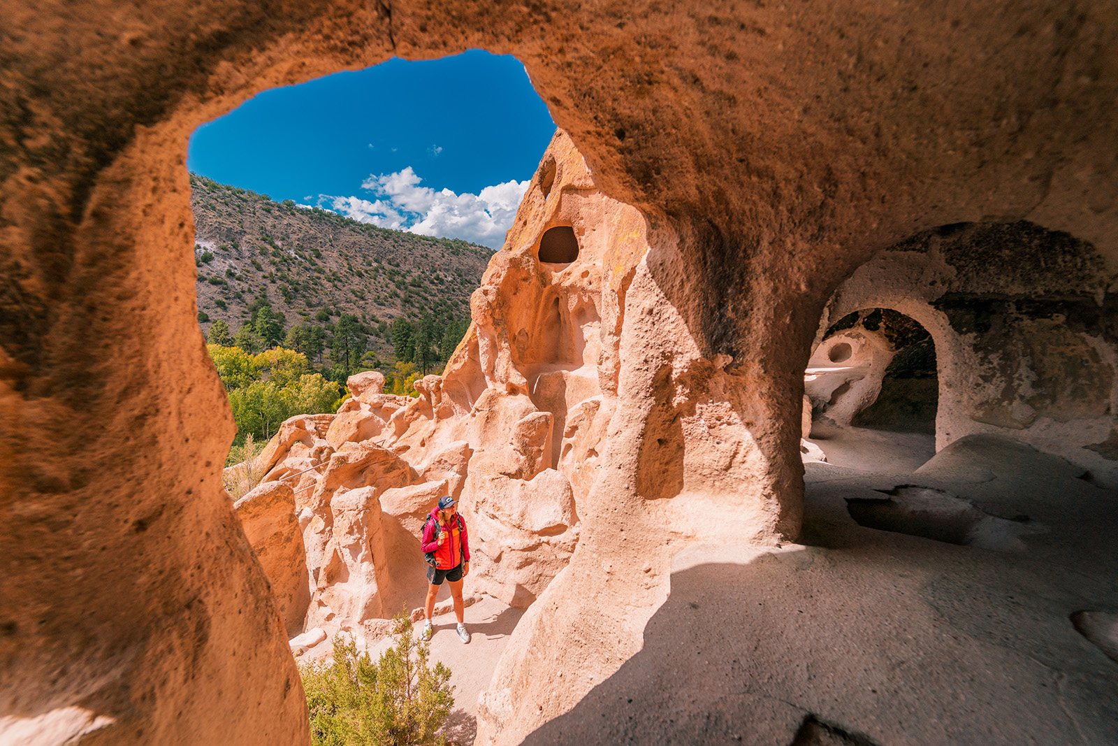 Woman in a red jacket looking at orange craters in a canyon