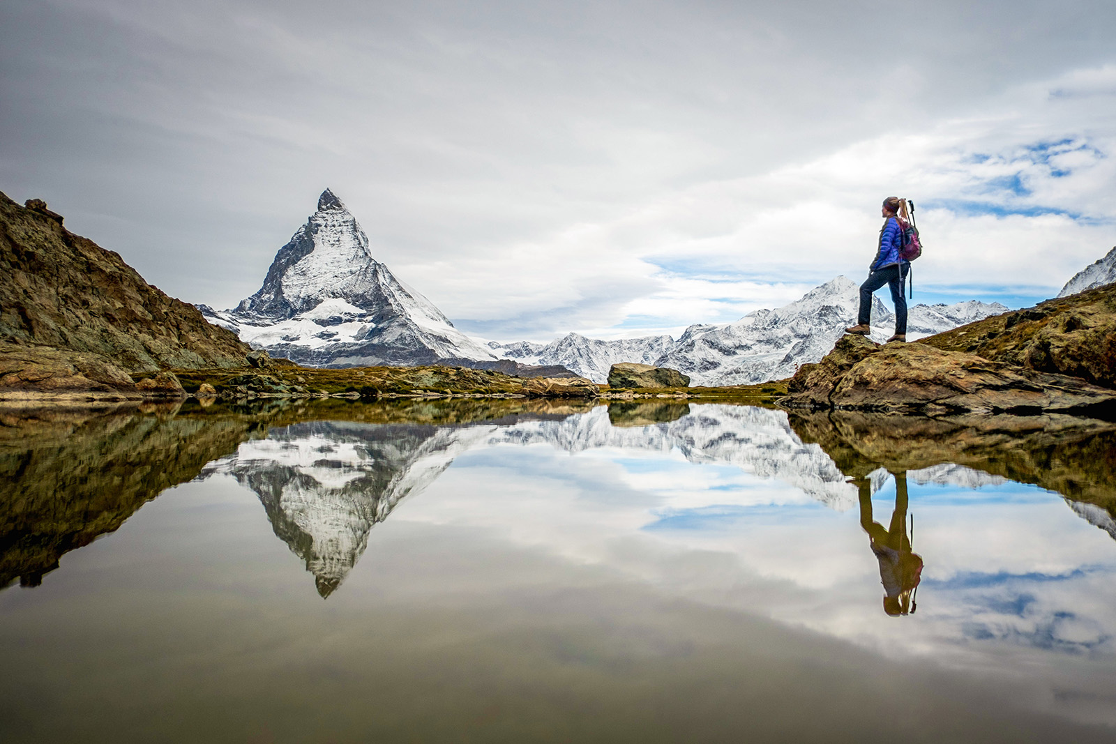 A backroads guest on a hike stops to admire snow capped peaks in the distance