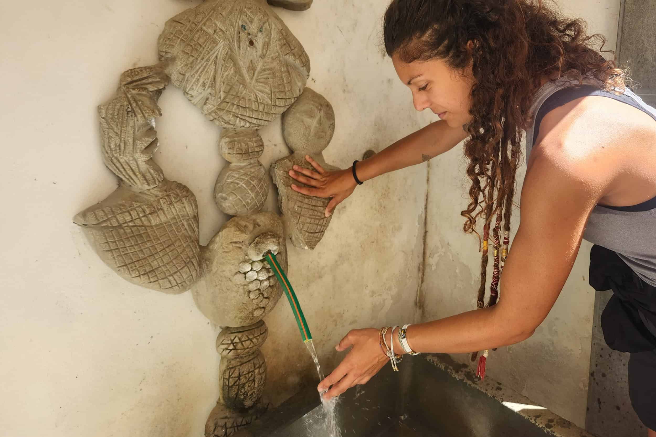 Woman touching water from a stone water fountain